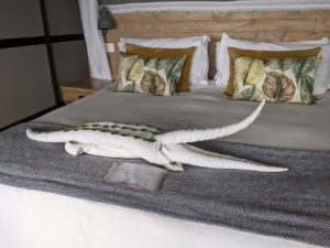 A crocodile made out of towels, with green leaves in three rows on its back.