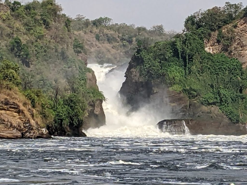 Murchison Falls, all of the Nile plunging through a narrow gap, partly hidden in the mist.