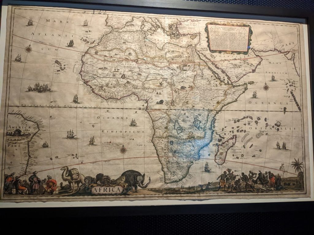 A map of Africa; the oceans are decorated with pictures of ships, and the lower border with native people and animals.