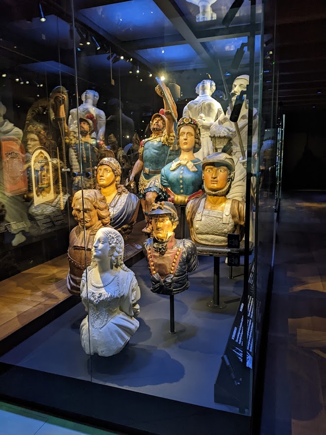 A display of nine figureheads in various styles.