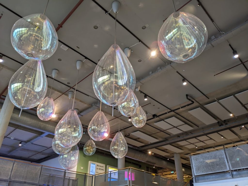 A collection of iridescent, tear-drop shaped (or pear shaped) glass bulbs hanging from the ceiling.