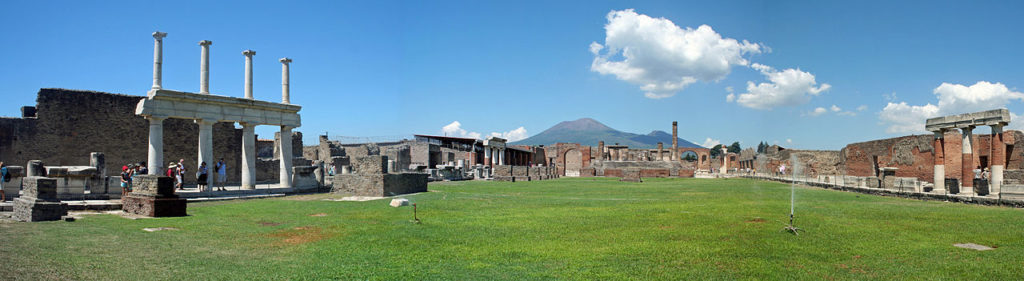 A grassy rectangle surrounded on three sides by ruins, with a volcano in the background.